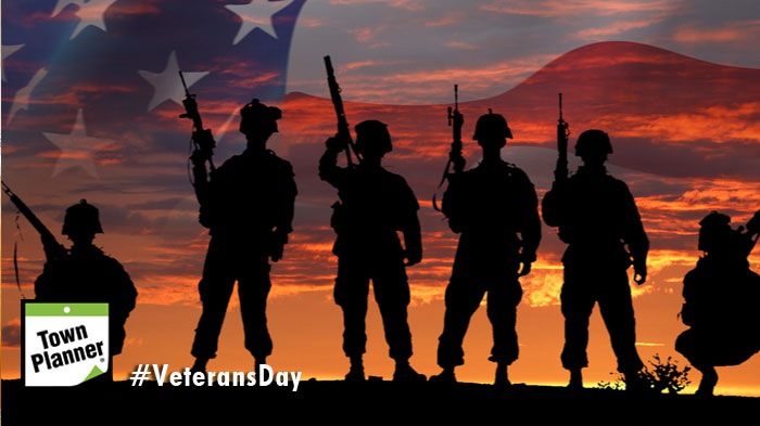 Soldiers standing shadowed in front of American Flag background